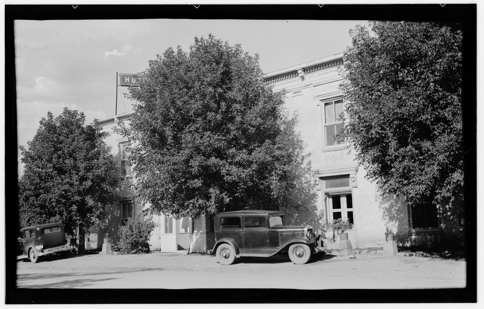 The St. James Hotel exterior in August 1936, with trees and automobiles along the street.